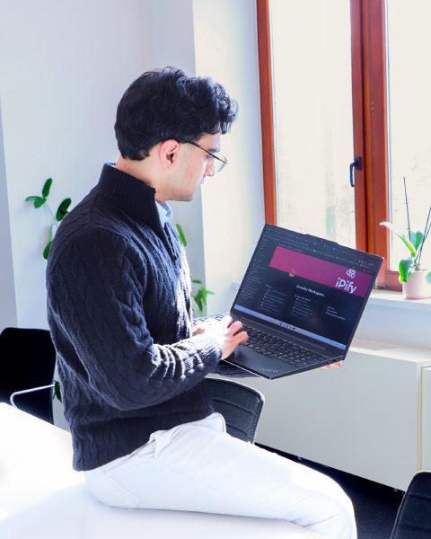 An iPify specialist working at a laptop, in control of the work